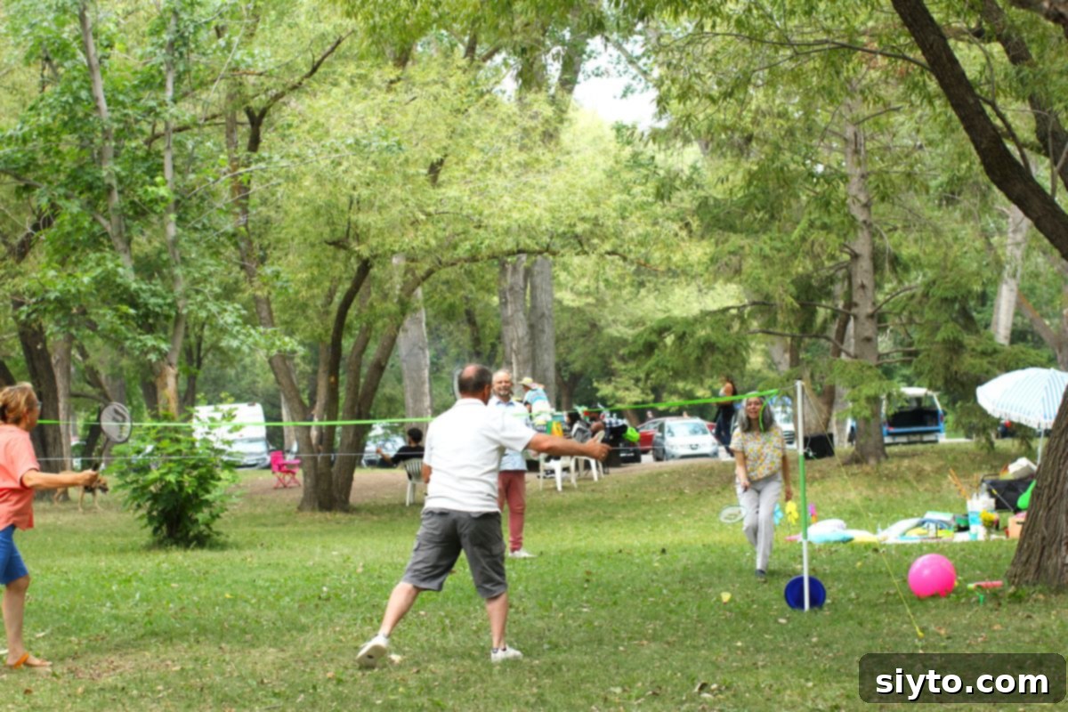 Two people actively playing badminton outdoors, surrounded by green grass, enjoying a fun picnic activity.