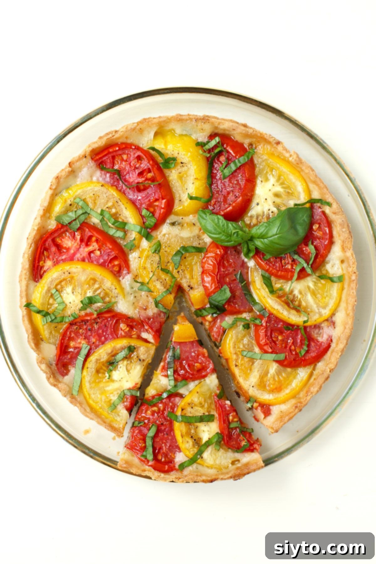 Rustic Tomato Tart 2 A beautifully baked tomato tart with a slice gently pulled out, showcasing the layers of crisp pastry, melted cheese, and juicy tomatoes.