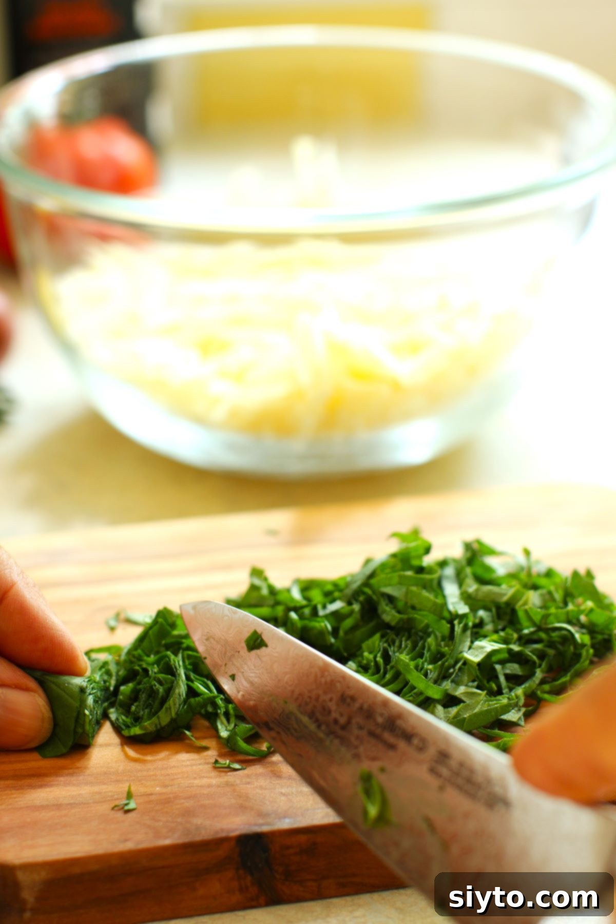 Rustic Tomato Tart 8 Close-up of hands expertly chiffonading fresh basil leaves by rolling them tightly and slicing finely.