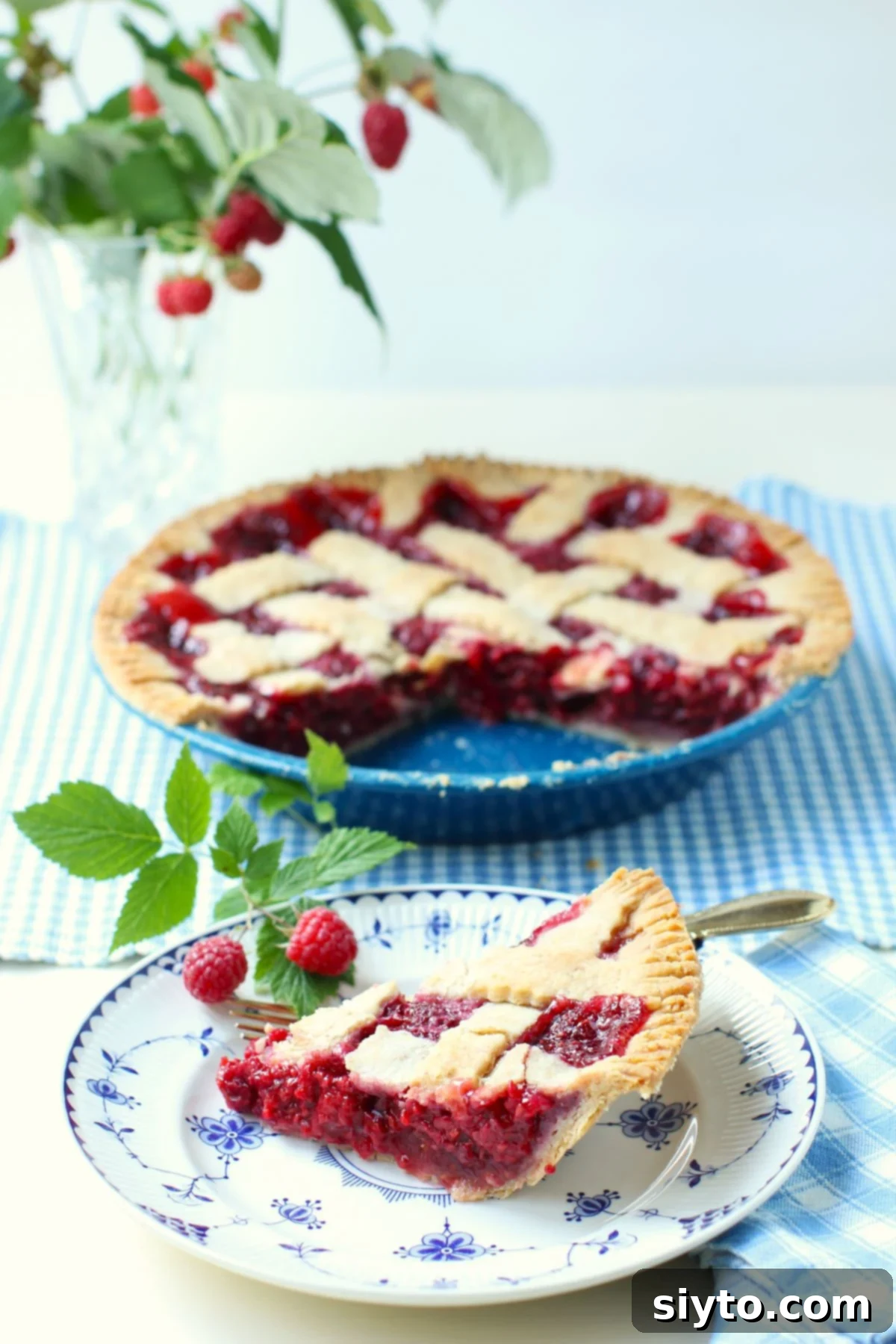 Raspberry Pie in a tin, with a slice on a plate in front. Delicious homemade raspberry pie.
