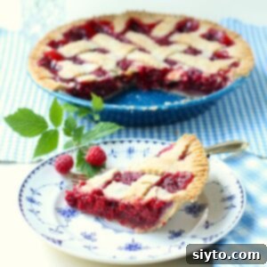 Slice of Raspberry Pie on a plate in front of the whole pie.