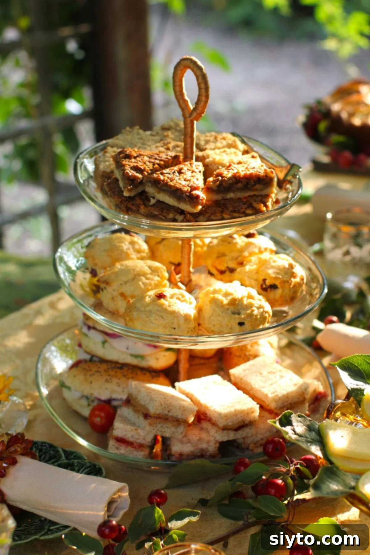 A beautiful 3-tiered cake stand brimming with Afternoon Tea delights, with delicious Butter Pecan Bars showcased on the top tier.