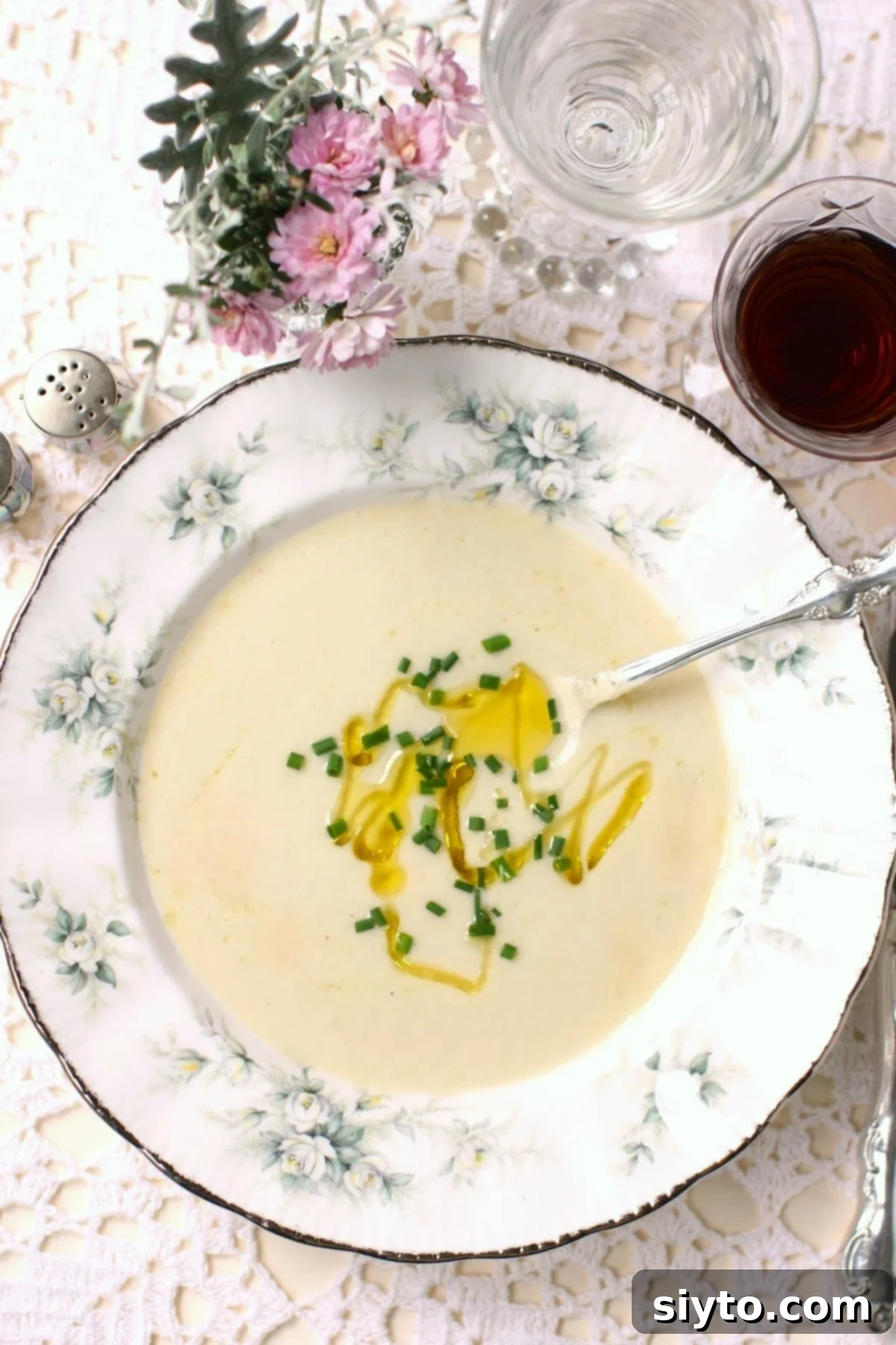 top down view of a bowl of soup with olive oil drizzle and chopped chives.
