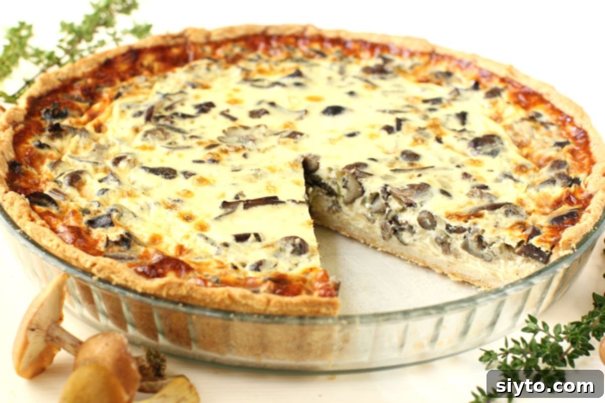 Foraged Fungi Quiche with a Gluten-Free Base 10 the mushroom quiche in a glass pan, with a slice cut out of it.