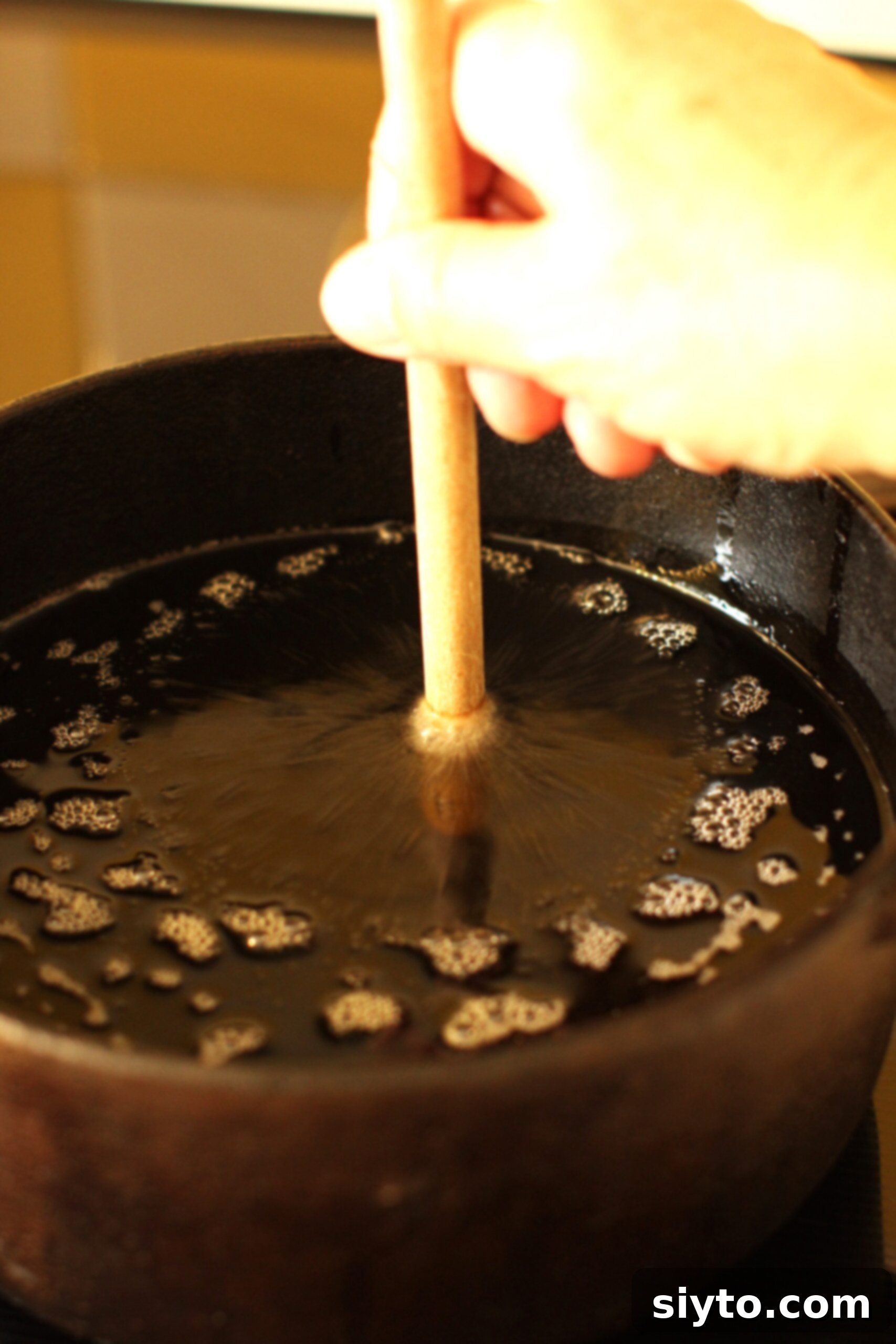 Holding the handle of a wooden spoon in the oil to see if bubbles come up around it.