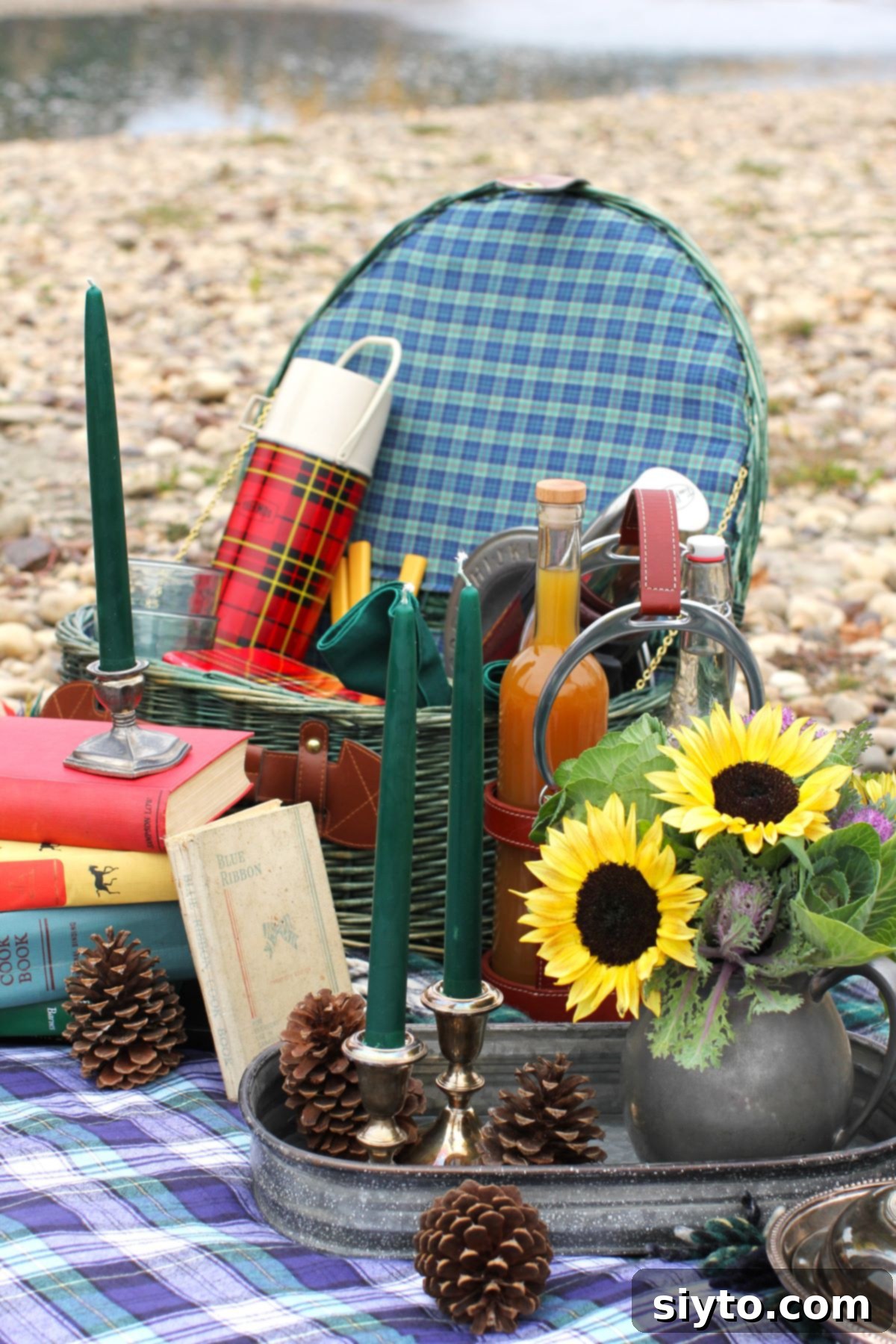Pewter pitcher of sunflowers, green picnic basket, and thermoses.