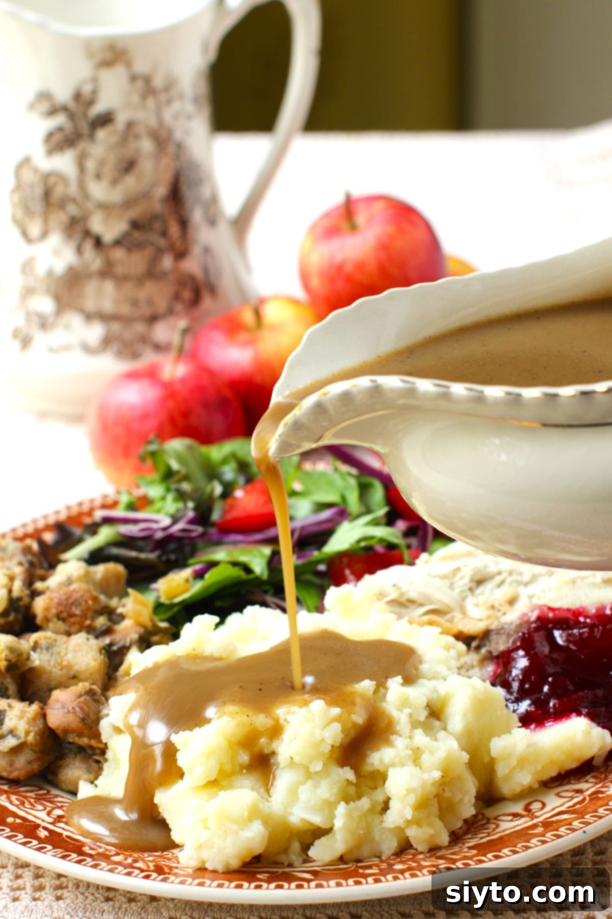 Apple Day From Press to Gravy Pot 2 Pouring apple cider gravy onto a pile of mashed potatoes on a fully loaded plate of turkey dinner.