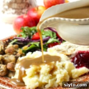 Apple Day From Press to Gravy Pot 13 Thumbnail photo of gravy boat pouring apple cider gravy onto a mound of mashed potatoes on a plate full of turkey dinner.