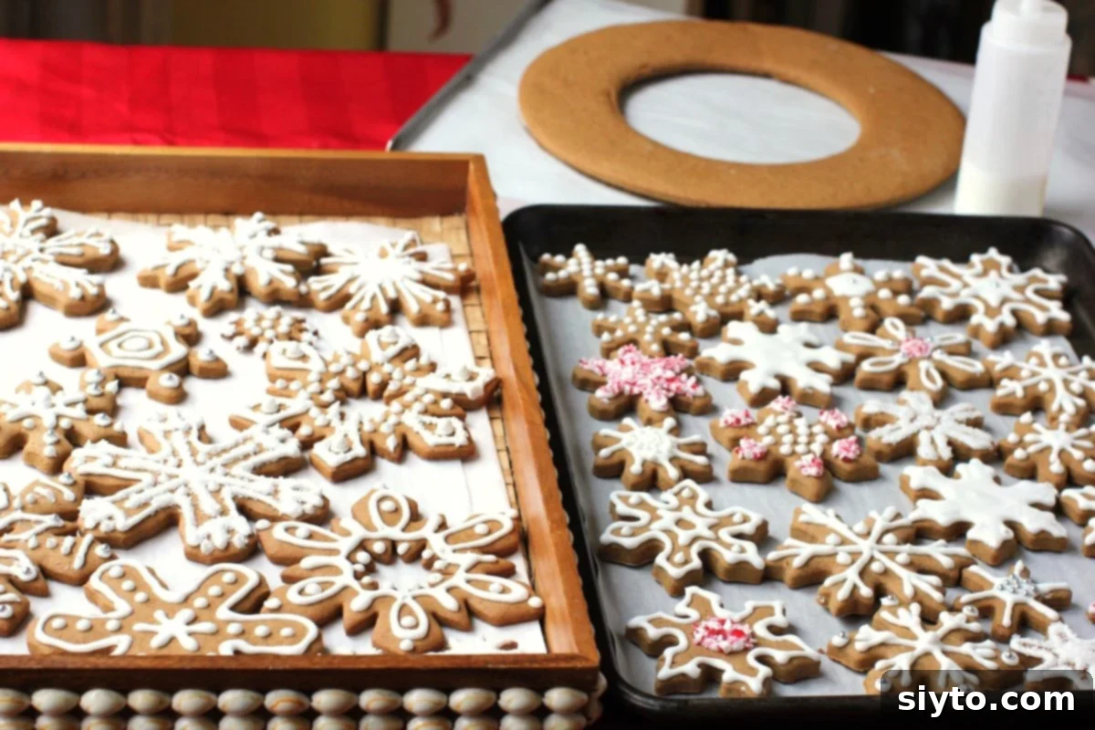 Two pans of elaborately decorated snowflake gingerbread cookies, showcasing various icing designs and sprinkles.