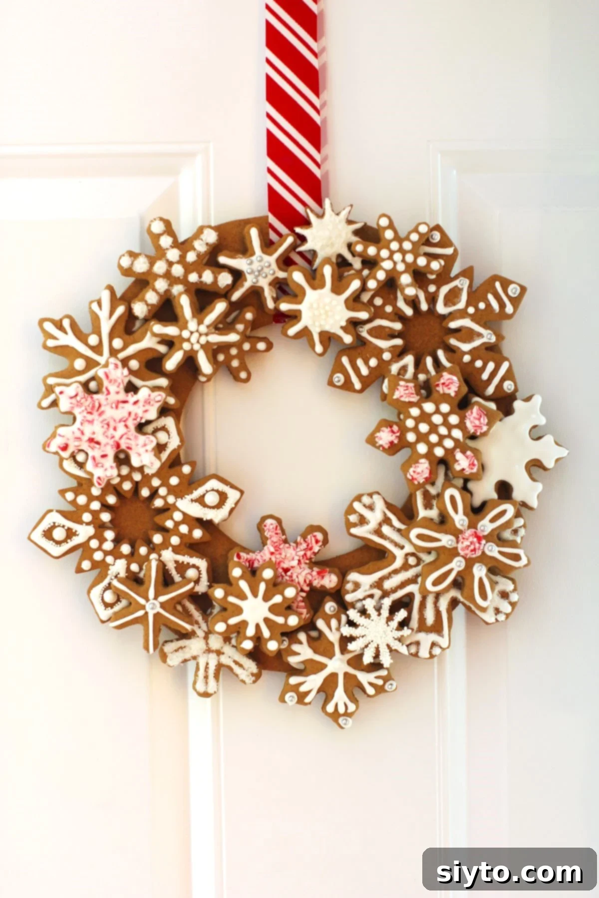 Our beautiful Gingerbread Snowflake Cookie Wreath elegantly hanging on a white door, ready to greet guests.