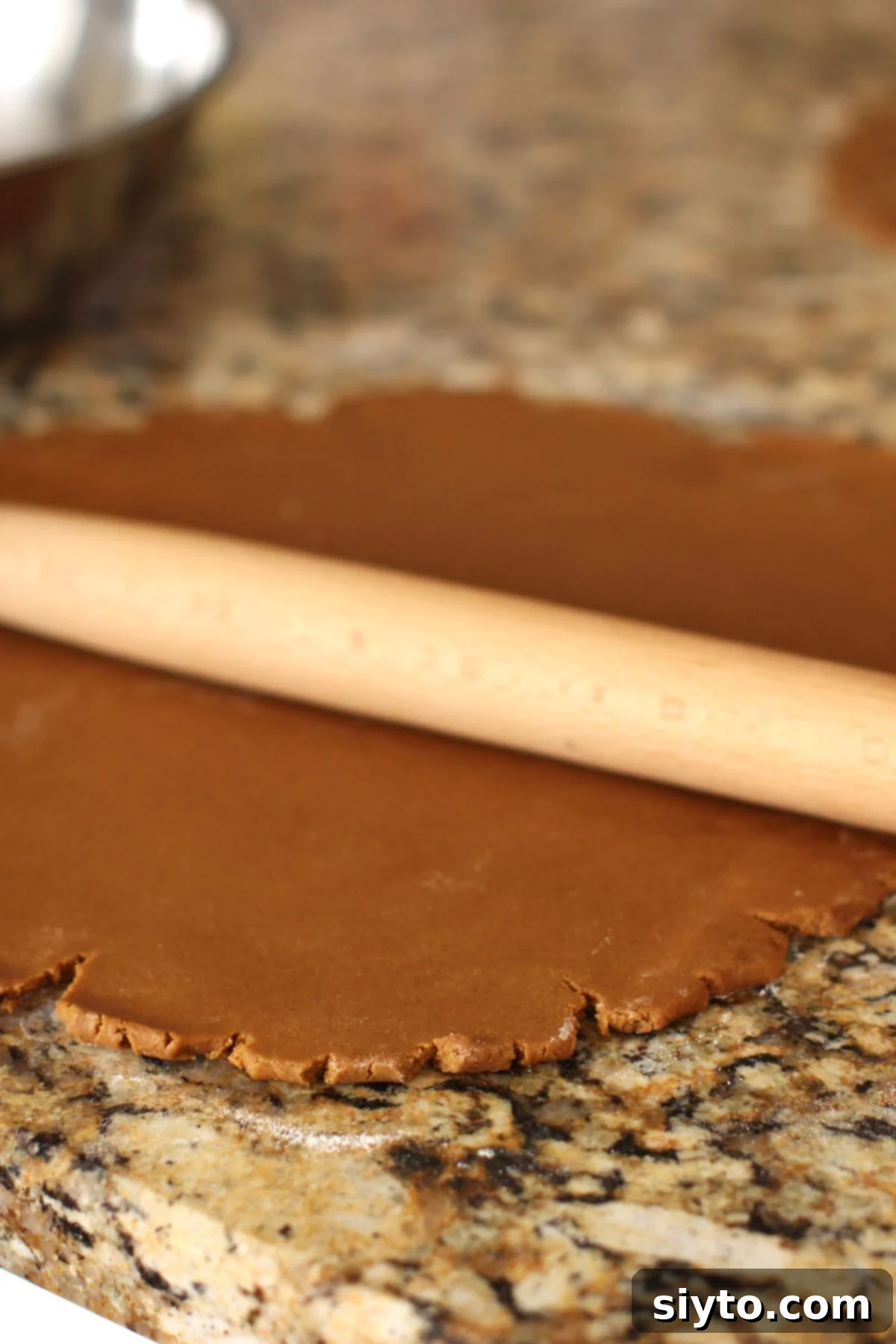 Rolling out the gingerbread cookie dough with a French rolling pin, ensuring even thickness.