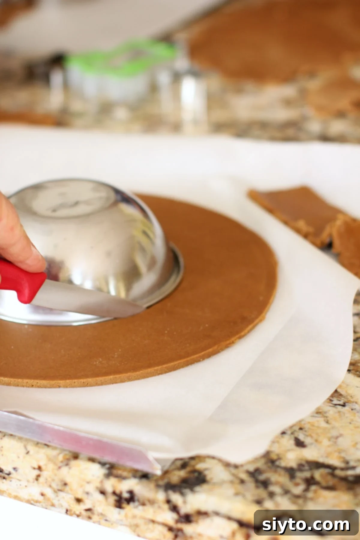 Cutting around a small bowl inside the big circle of gingerbread cookie dough to make the wreath form, creating the inner ring.