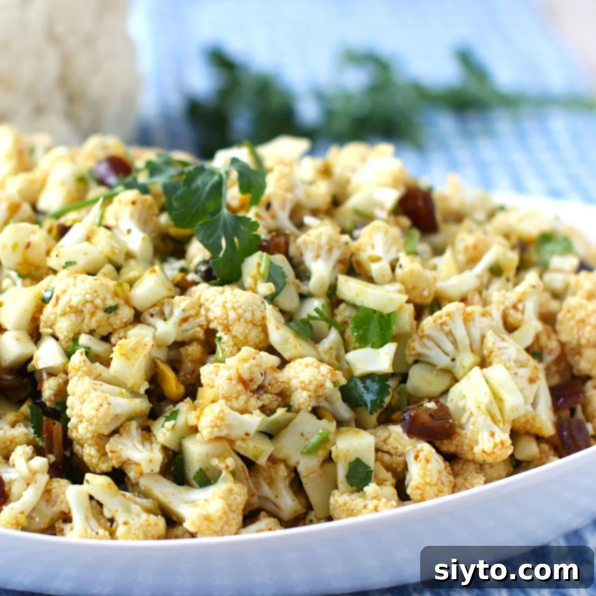 Thumbprint of close-up of bowl of cauliflower salad.