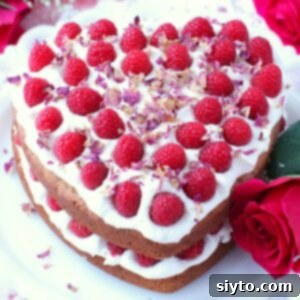 A stunning Raspberry Rose Heart Cake, beautifully decorated with fresh raspberries and rose petals.