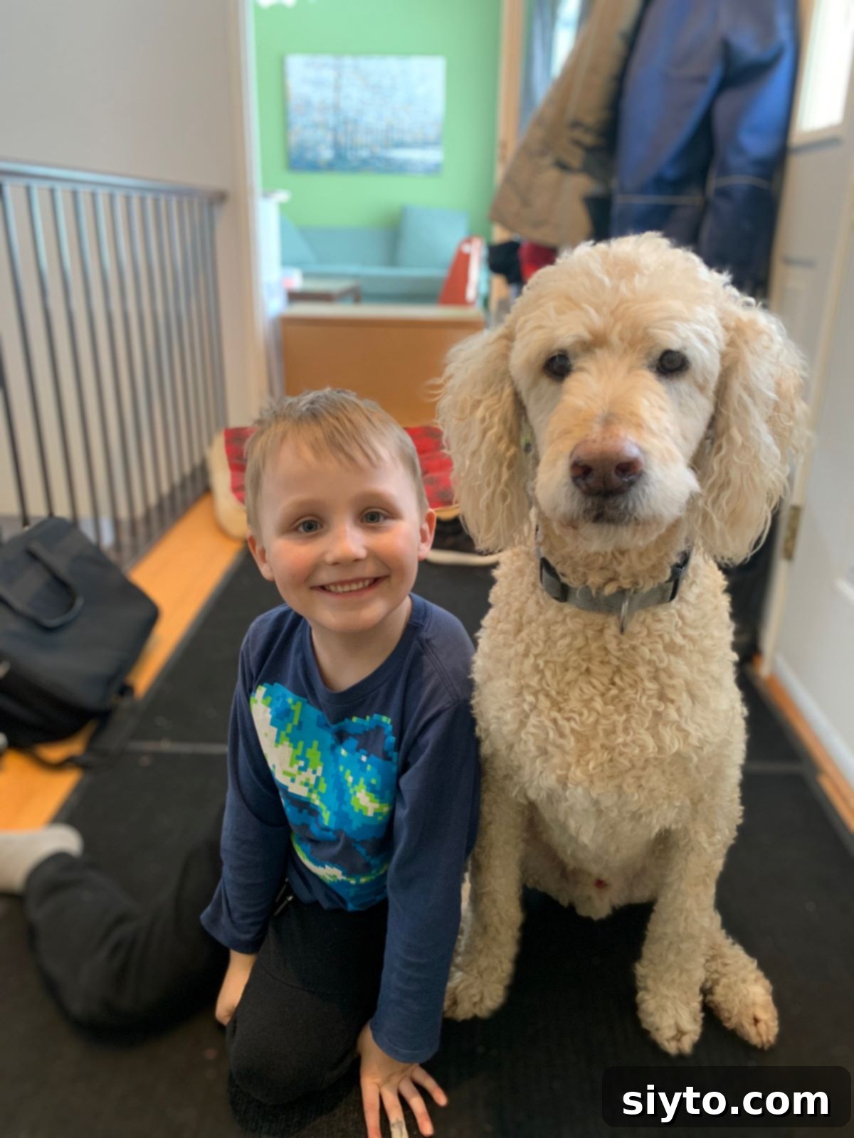 Caleb sitting happily beside his dog Charlie, who is attentively looking at him, eagerly awaiting a treat.