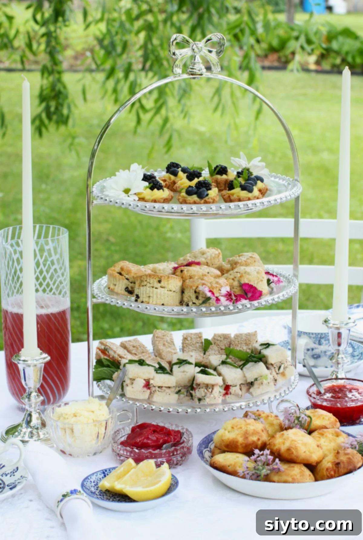 3-tiered cake stand with tea sandwiches, scones, and sweets, on tea table