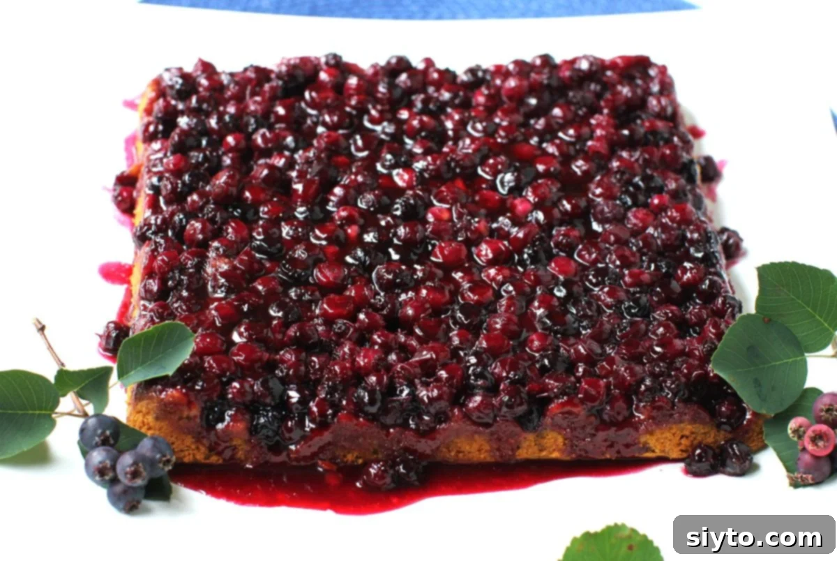 The square cake flipped over onto a serving platter so the juicy glazed berries are now on top.