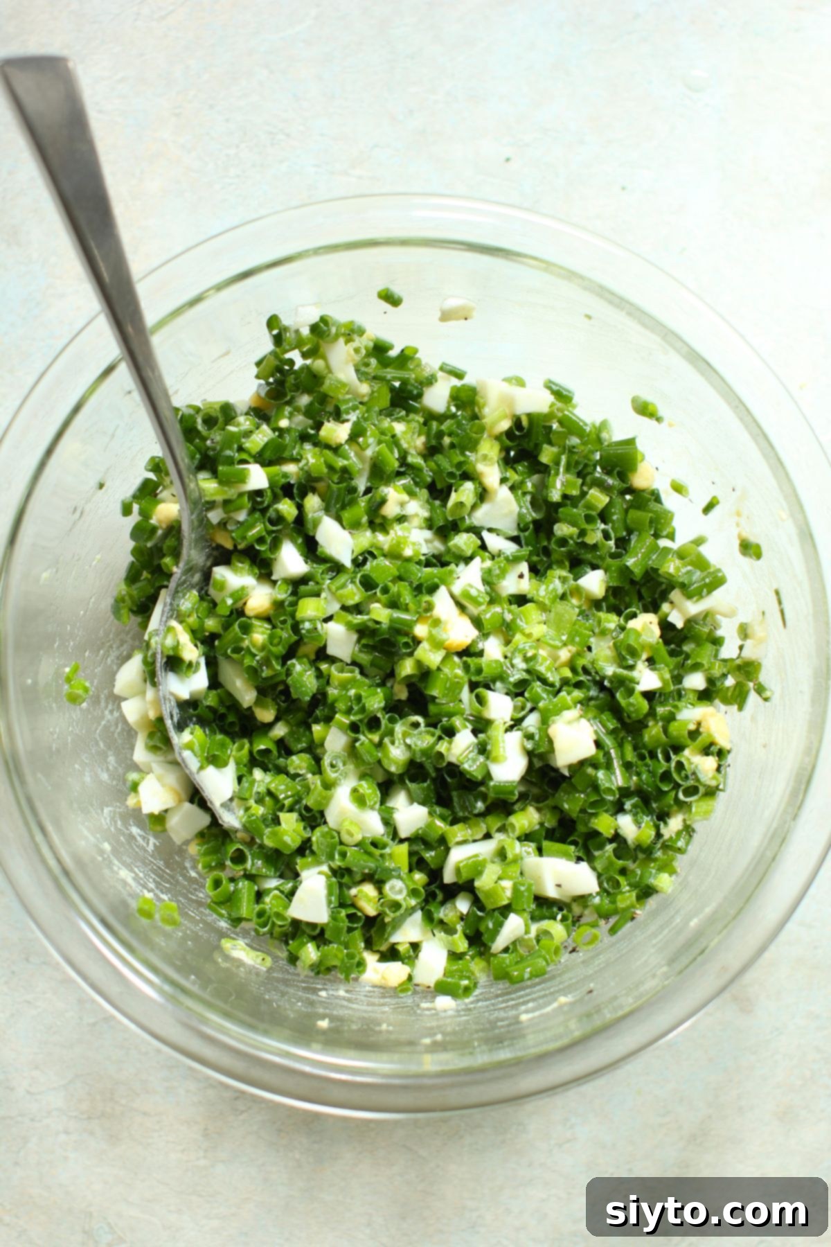 German Chive Salad (Schnittlauchsalat) fully mixed and ready to serve in a clear bowl.
