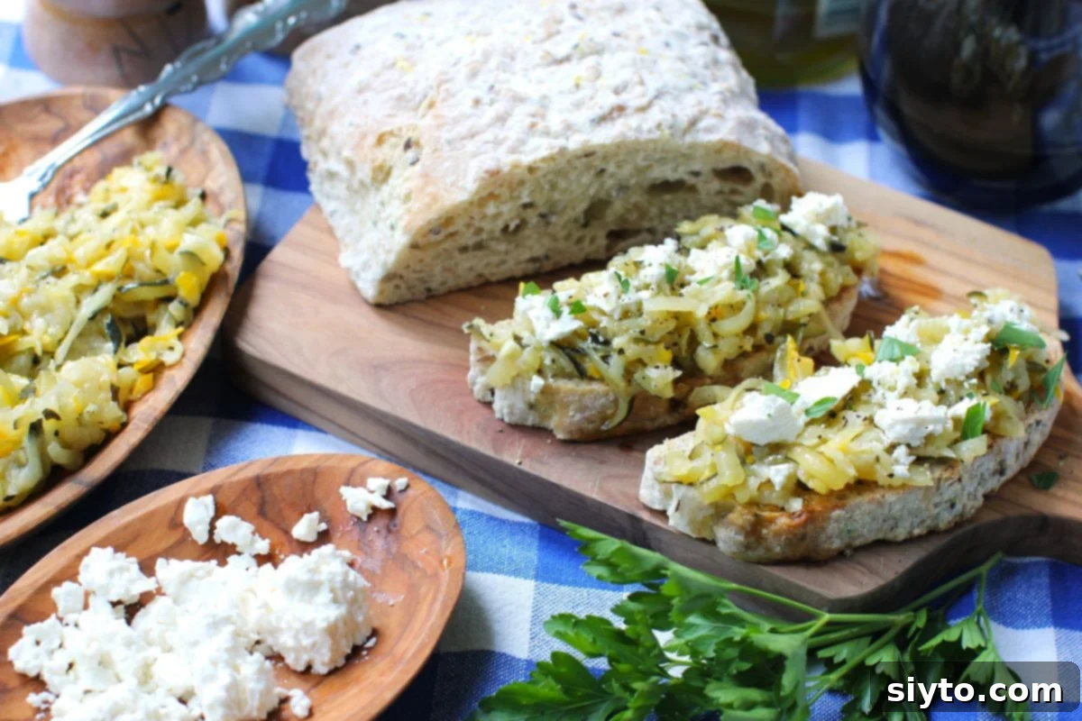 Velvety Zucchini Butter 10 A cutting board with loaf of bread and two slices of crostini with zucchini butter on top, feta crumbles, and parsley.