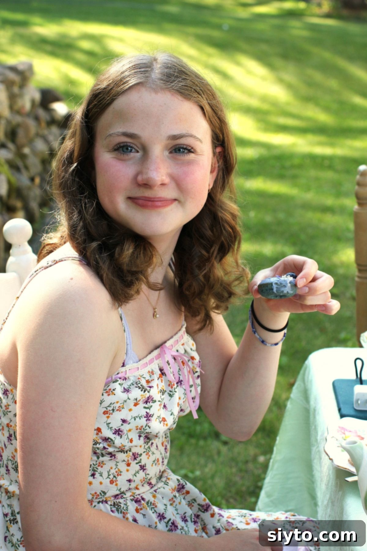 Amelia holding a single mini blue donut at the tea party, ready to enjoy the festive treat.