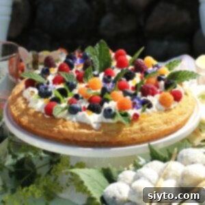 Thumbnail photo of almond cake decorated with berries and flowers.