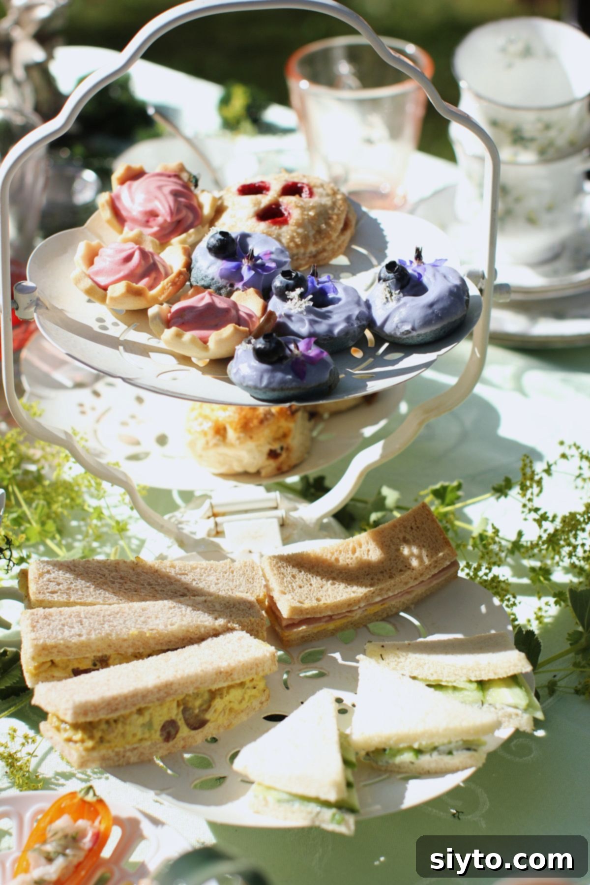 a 3-tiered stand loaded with finger sandwiches, scones, and sweet treats.