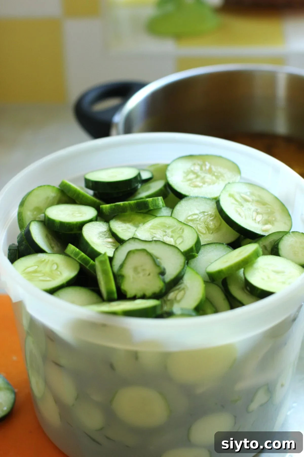 A plastic ice cream pail of sliced cucumbers.