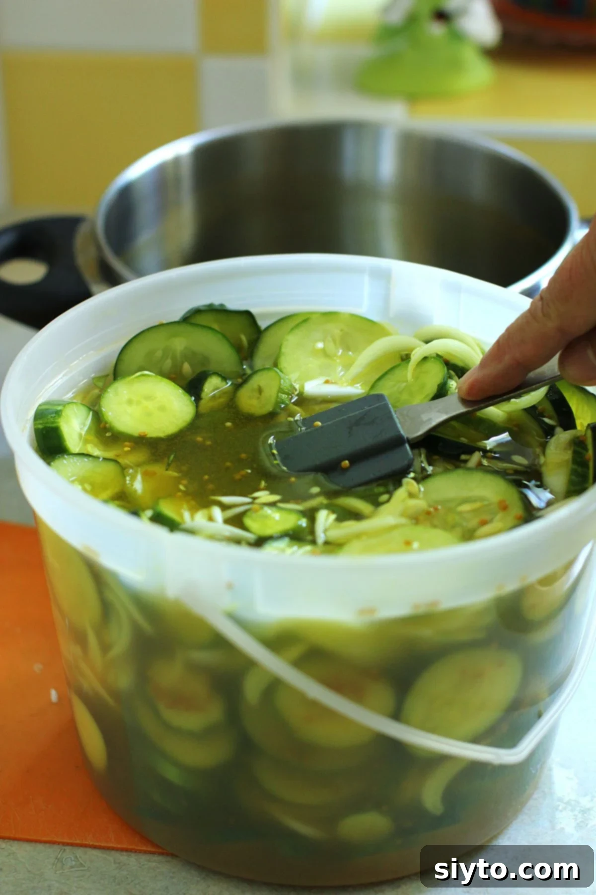 Pushing down on the cucumbers with a spatula to submerge them in the brine.