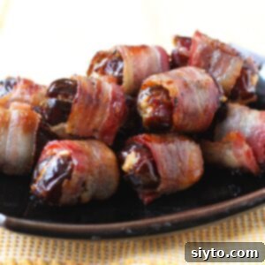 Bacon wrapped dates piled on a black platter, thumbnail photo.