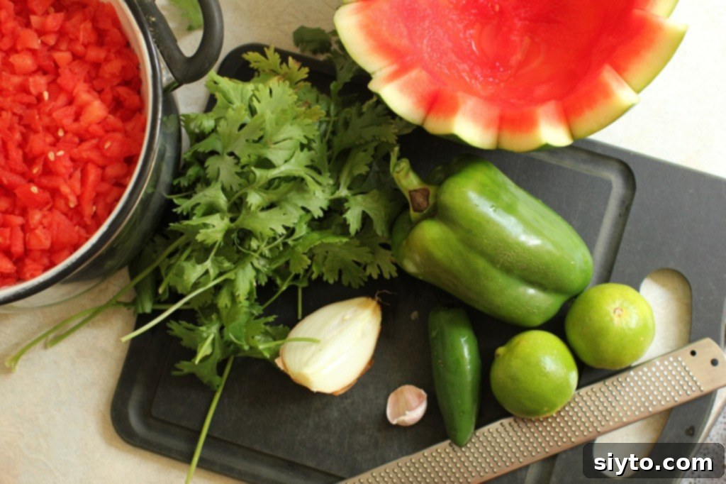 All fresh ingredients for watermelon salsa, including lime, garlic, onion, and peppers, arranged on a cutting board