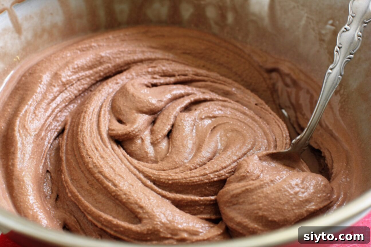 A bowl of chocolate ice cream, visibly stirred until smooth and creamy, ready to be spread into the cake layers.